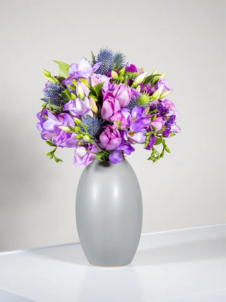 Bouquet viola di tulipani freesie eryngium in vaso grigio